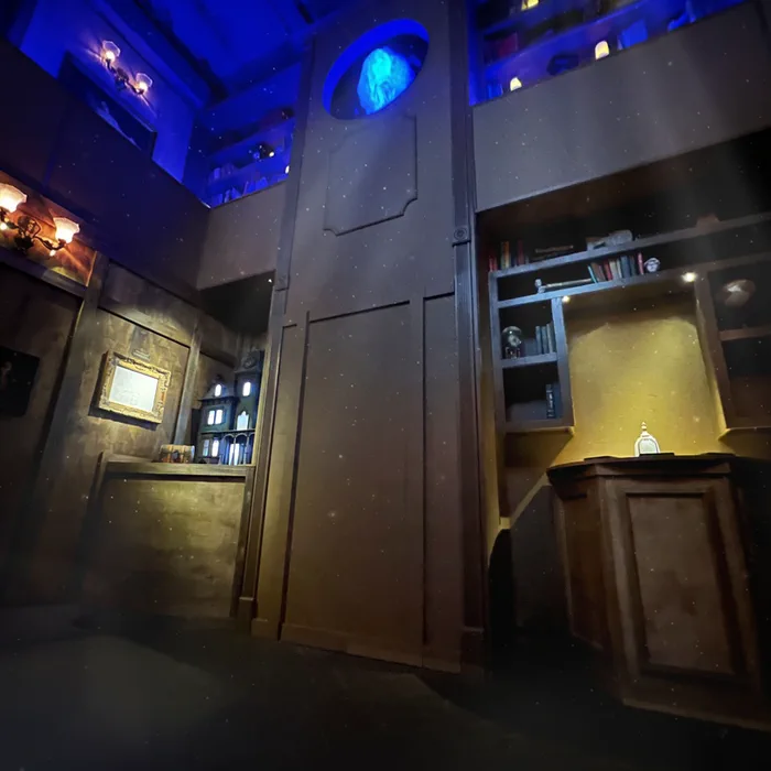Tall hidden door with glowing ghostly figure in upper window inside Victorian escape room set